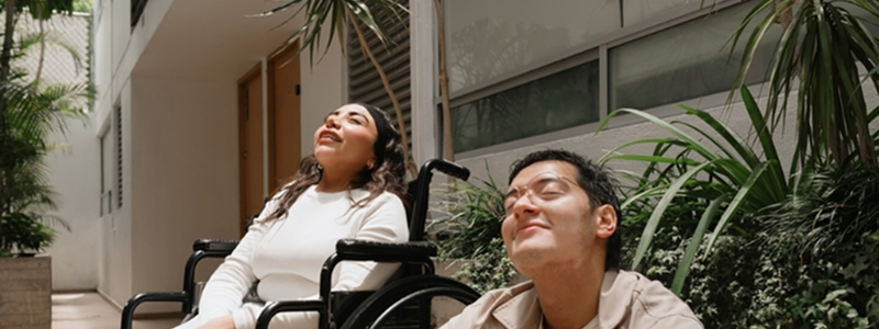 A woman in wheelchair and a man relaxing and enjoying the sunshine.