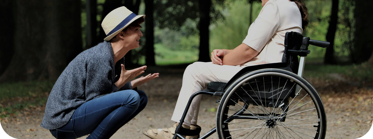 A young man is excitedly gesturing while speaking to a person in a wheelchair.