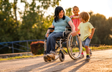A woman in a wheelchair on a path with 2 young children.