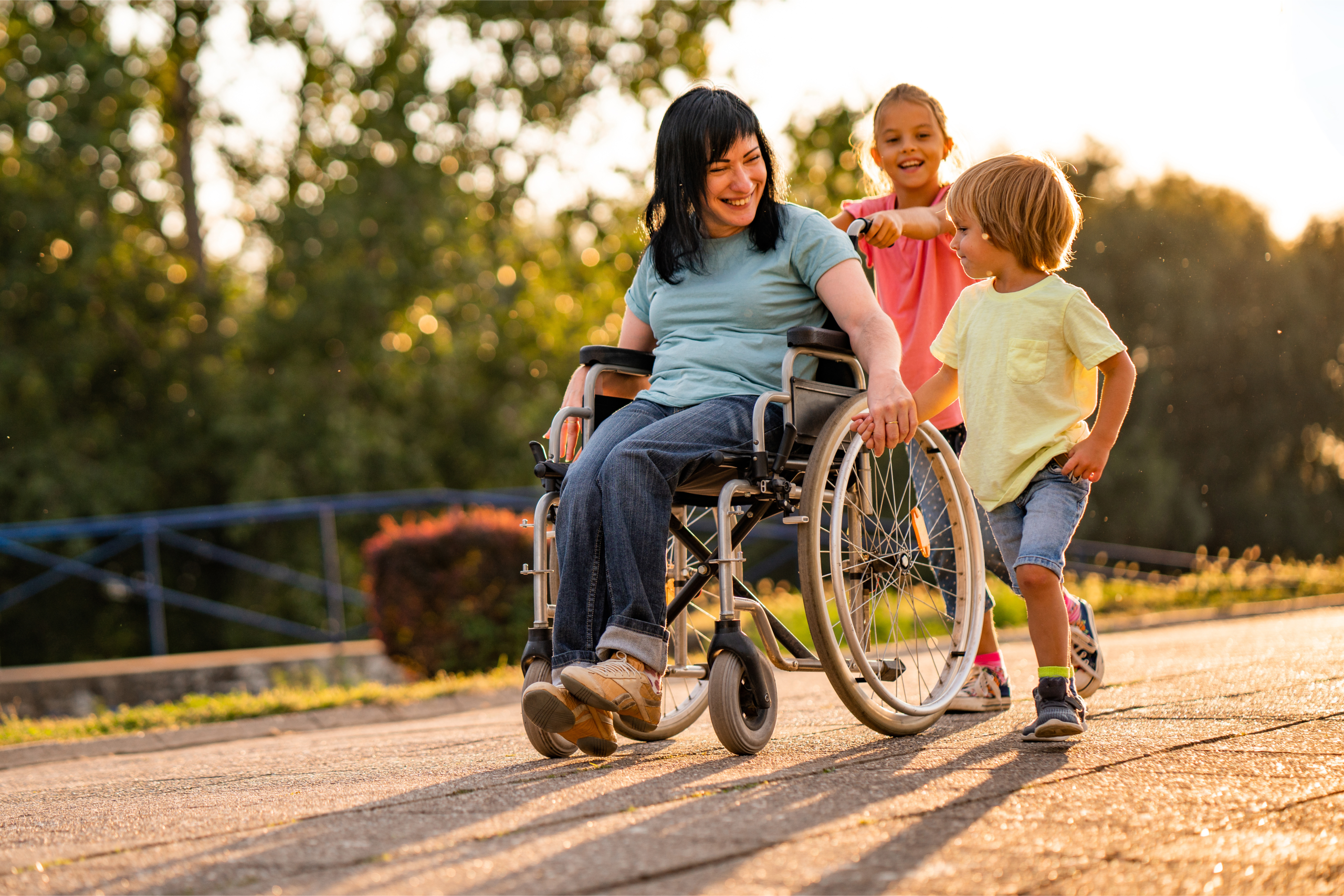 A woman in a wheelchair on a path with 2 young children.