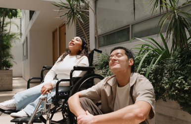 A woman in wheelchair and a man relaxing and enjoying the sunshine.